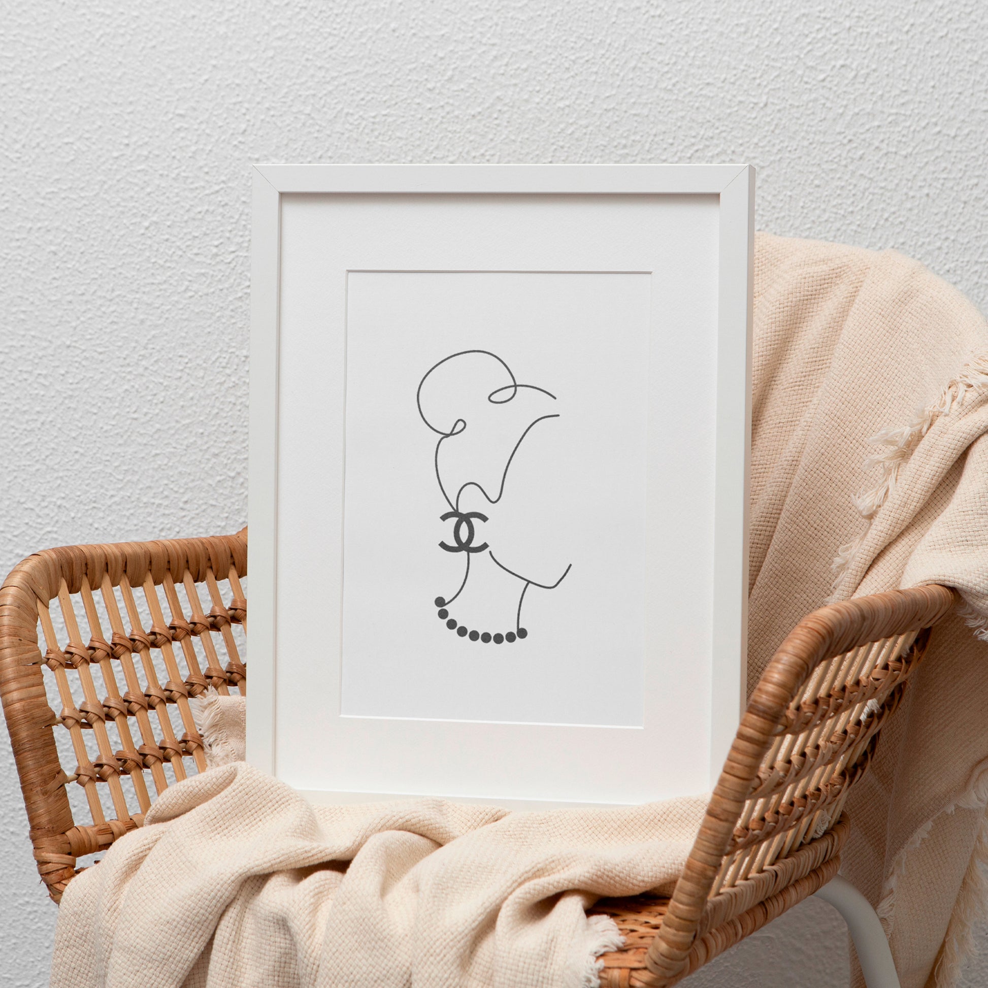 line art print in white frame leaning on chair